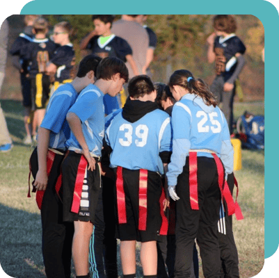 Children huddled up during a co-ed flag football game