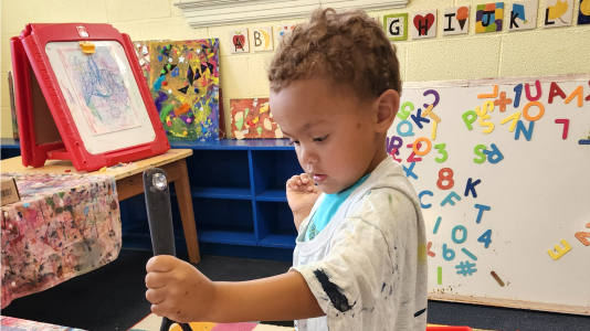 Young child painting during art class