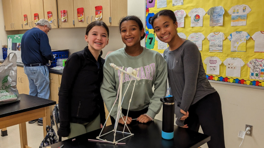 Middle School girls smiling next to a science project