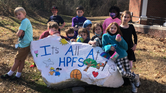 Students smiling around a rock that says, 